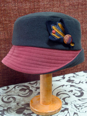 A olive and brown cloche style wool hat on a stand