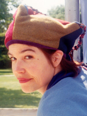 Close up of Gwendolyne modelling a green and red Four Corner Hat
